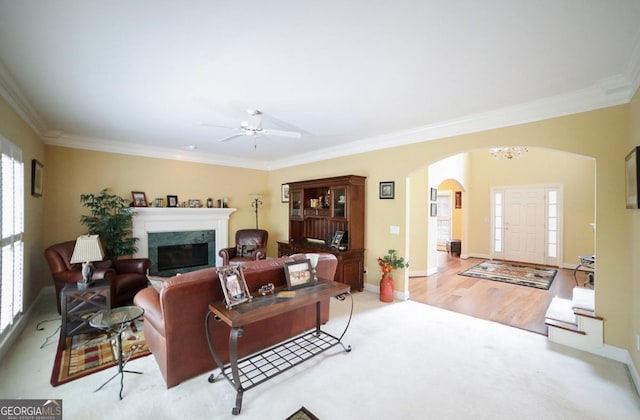 living room featuring ceiling fan with notable chandelier, ornamental molding, and light hardwood / wood-style flooring