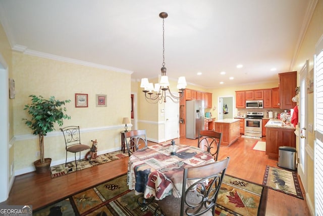 dining area with a notable chandelier, light hardwood / wood-style floors, and ornamental molding