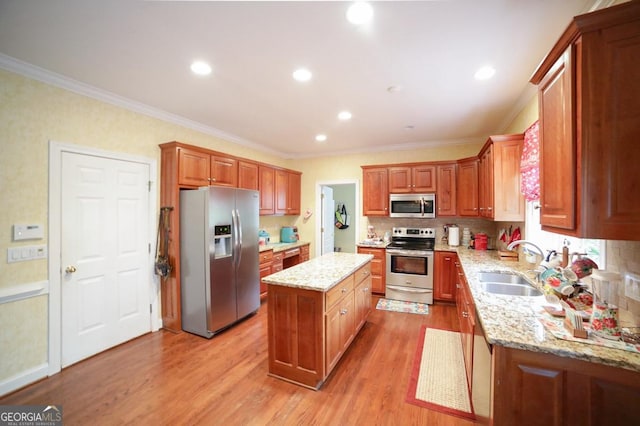 kitchen with ornamental molding, stainless steel appliances, sink, light hardwood / wood-style flooring, and a kitchen island