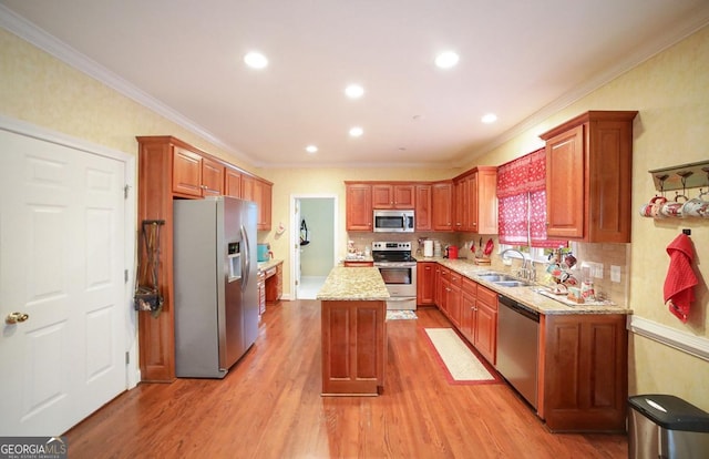 kitchen featuring a center island, crown molding, light stone countertops, light wood-type flooring, and appliances with stainless steel finishes