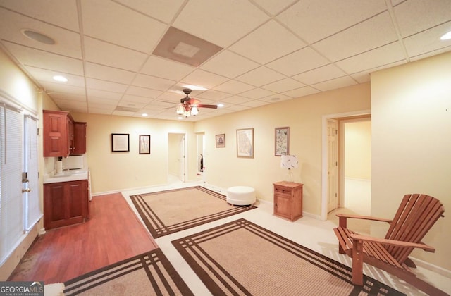 sitting room with ceiling fan, a drop ceiling, and carpet floors