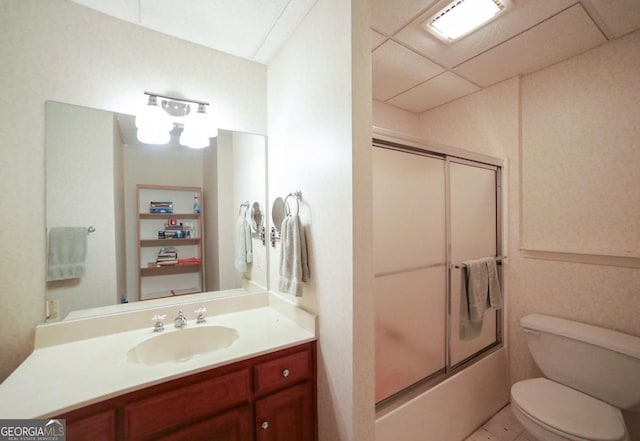 full bathroom featuring a paneled ceiling, vanity, toilet, and enclosed tub / shower combo