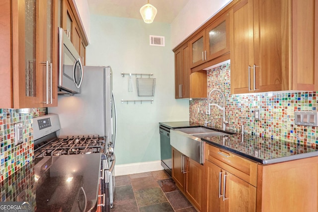 kitchen featuring dark stone countertops, backsplash, sink, and appliances with stainless steel finishes