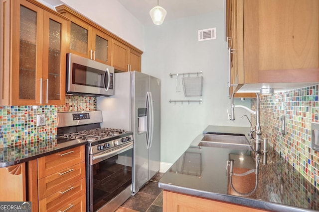 kitchen with pendant lighting, stainless steel appliances, sink, and backsplash