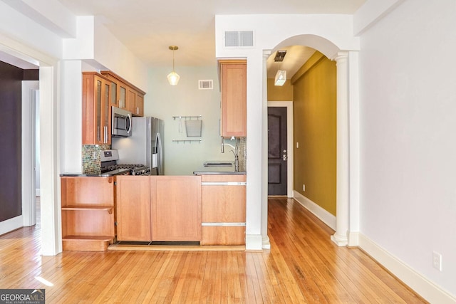 kitchen with sink, ornate columns, pendant lighting, stainless steel appliances, and backsplash