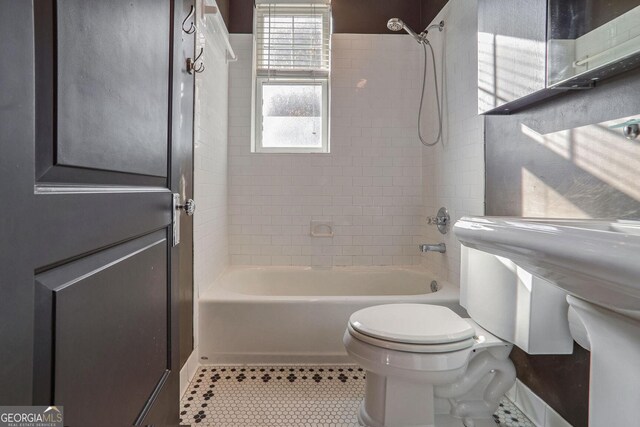 bathroom featuring tiled shower / bath, tile patterned floors, and toilet