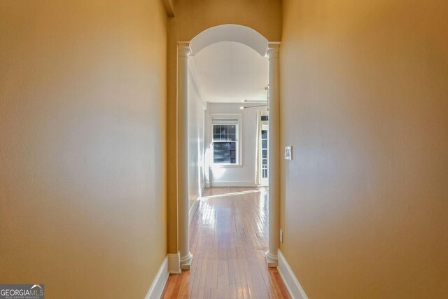 hallway featuring decorative columns and light wood-type flooring