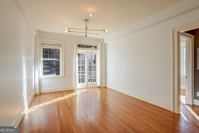 spare room with a healthy amount of sunlight, light hardwood / wood-style flooring, and french doors