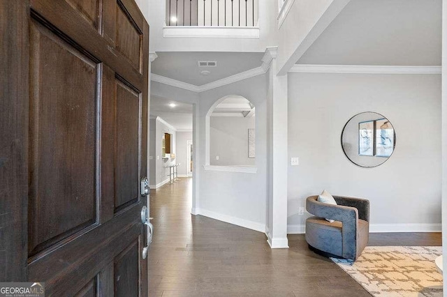 foyer entrance with crown molding and dark wood-type flooring