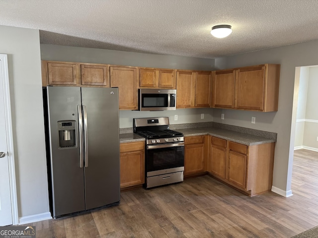 kitchen with appliances with stainless steel finishes, dark hardwood / wood-style floors, and a textured ceiling