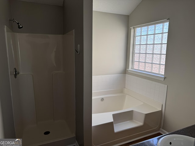 bathroom with vaulted ceiling, shower with separate bathtub, and a textured ceiling