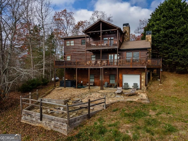 back of house featuring a lawn, a garage, a balcony, a patio area, and a deck