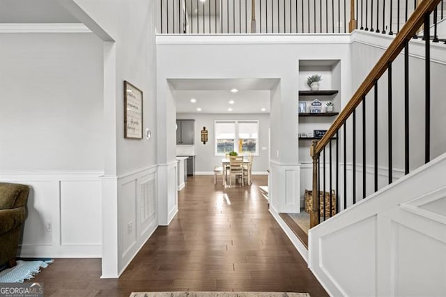 entryway with crown molding, a towering ceiling, and dark hardwood / wood-style floors