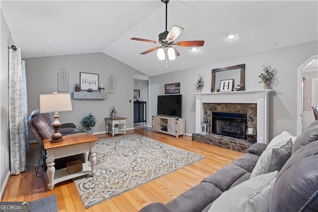 living room with a fireplace, ceiling fan, hardwood / wood-style floors, and lofted ceiling