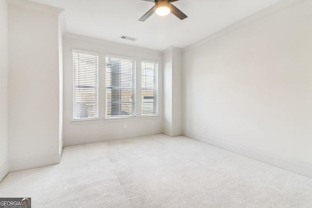 carpeted spare room with ceiling fan and ornamental molding