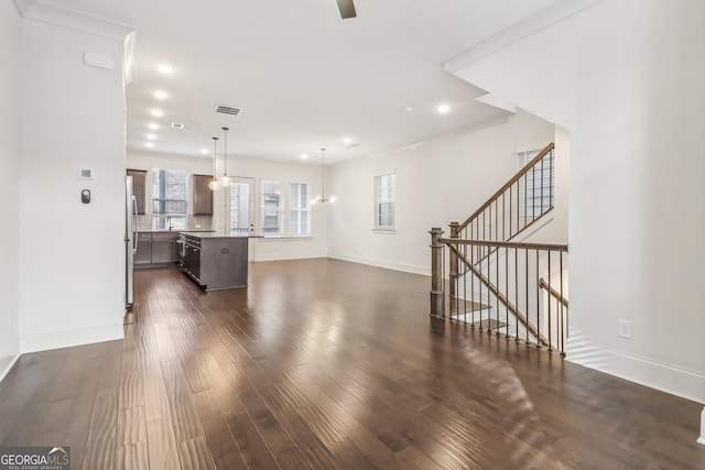 kitchen featuring stainless steel refrigerator with ice dispenser, hanging light fixtures, dark hardwood / wood-style floors, an island with sink, and dark brown cabinets