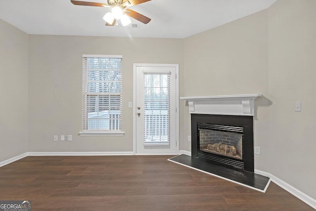 unfurnished living room featuring ceiling fan and dark wood-type flooring