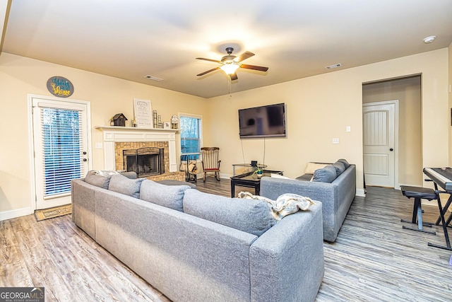 living room with ceiling fan, a fireplace, and hardwood / wood-style flooring