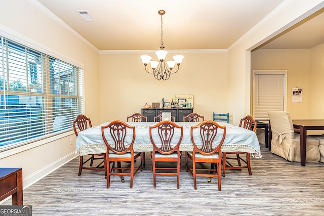 dining room with ornamental molding, a notable chandelier, and hardwood / wood-style flooring