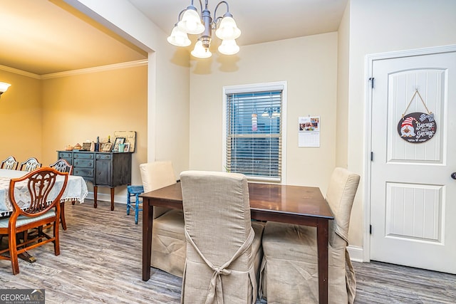 dining room with a notable chandelier, wood-type flooring, and crown molding