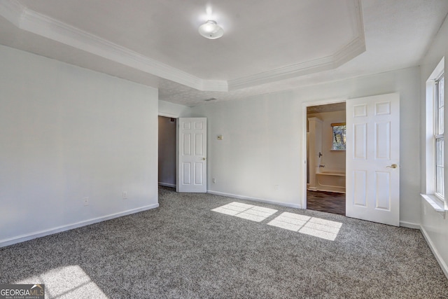 unfurnished bedroom with dark colored carpet and a raised ceiling