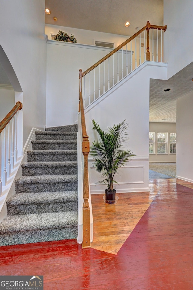 stairs with a towering ceiling and hardwood / wood-style flooring