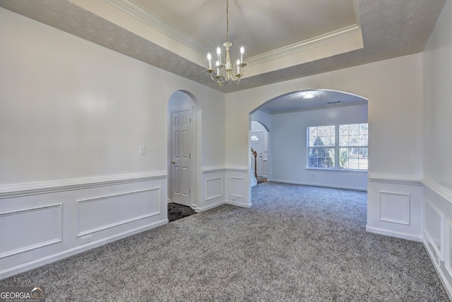 unfurnished room with carpet flooring, a notable chandelier, ornamental molding, and a tray ceiling