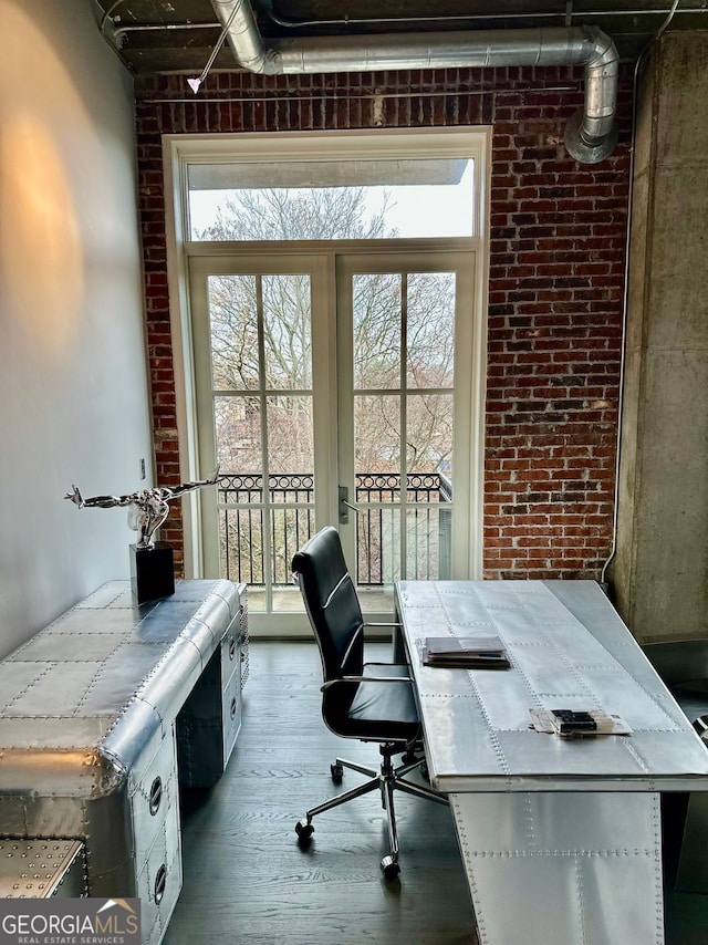 office area with dark hardwood / wood-style floors and brick wall