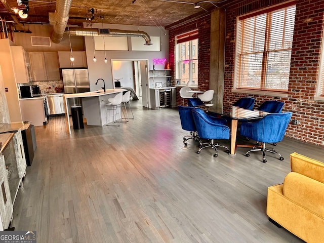 dining space with hardwood / wood-style floors, sink, a high ceiling, and brick wall