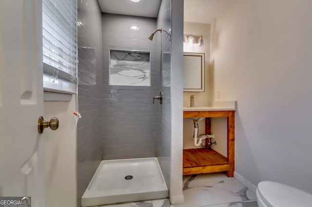 bathroom with a tile shower and toilet