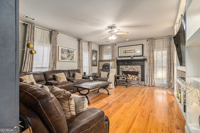 living room featuring hardwood / wood-style flooring, ceiling fan, and a fireplace