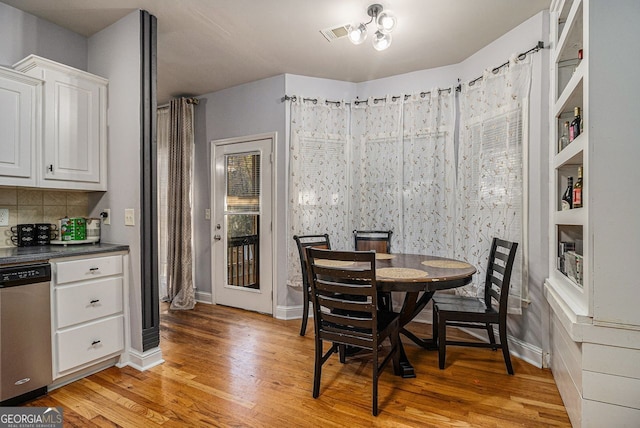 dining space with built in shelves and light hardwood / wood-style floors