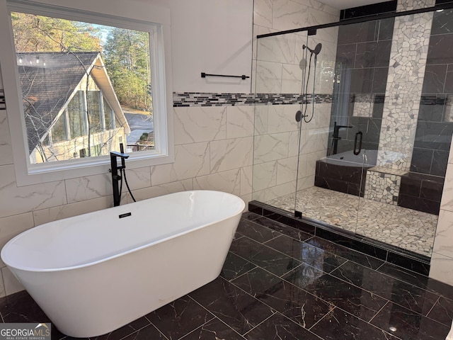 bathroom with plenty of natural light, independent shower and bath, and tile walls