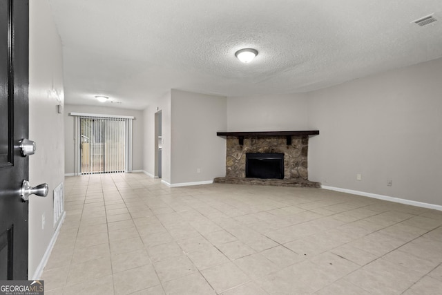 unfurnished living room with a textured ceiling, a stone fireplace, and light tile patterned flooring