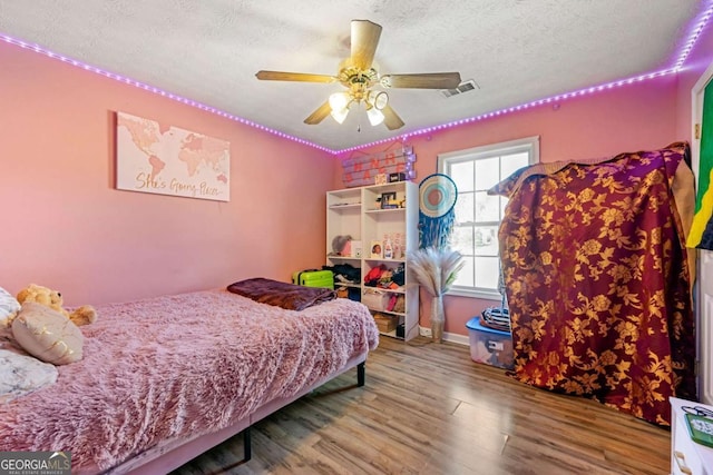 bedroom featuring ceiling fan, wood-type flooring, and a textured ceiling