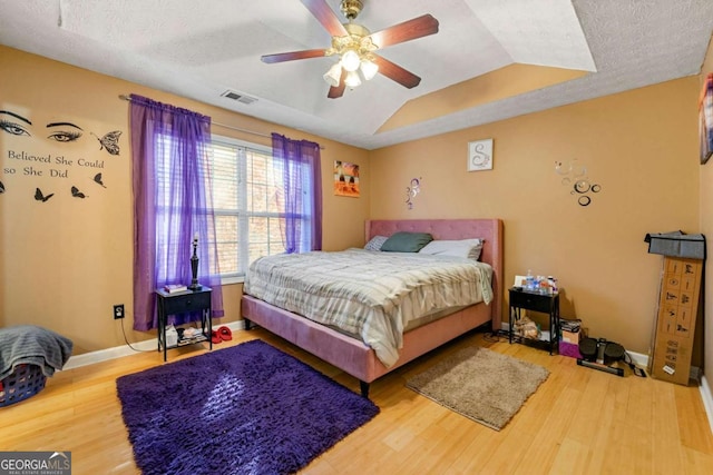 bedroom with ceiling fan, wood-type flooring, and a textured ceiling