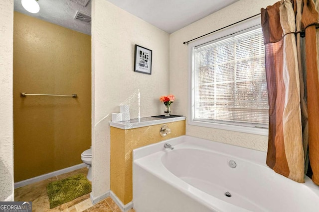 bathroom featuring toilet, plenty of natural light, and a tub