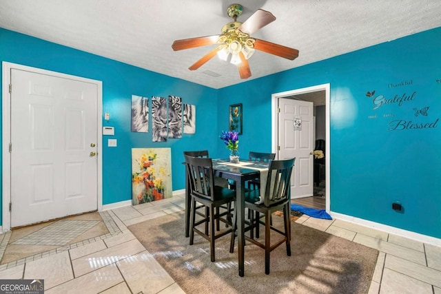 tiled dining space with ceiling fan and a textured ceiling