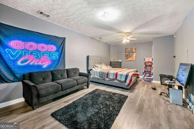 bedroom with hardwood / wood-style flooring, ceiling fan, and a textured ceiling