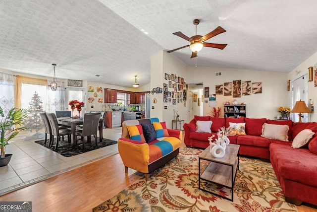 living room featuring a textured ceiling, light hardwood / wood-style flooring, ceiling fan, and lofted ceiling