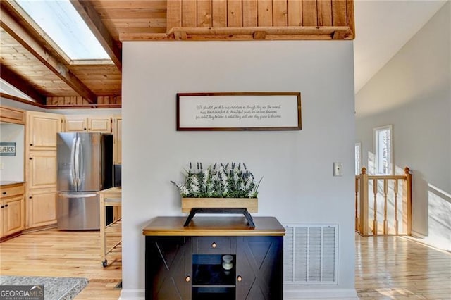 kitchen featuring light brown cabinets, wooden ceiling, a skylight, stainless steel fridge, and light hardwood / wood-style floors