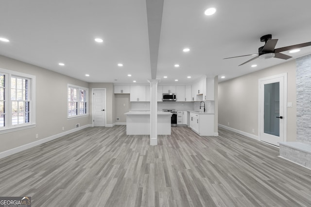 unfurnished living room with ceiling fan, sink, and light hardwood / wood-style floors