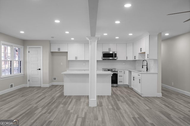 kitchen featuring sink, stainless steel appliances, a kitchen island, light hardwood / wood-style floors, and white cabinets