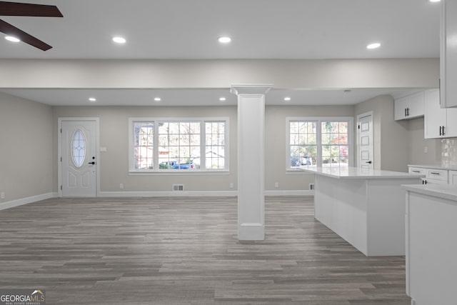 unfurnished living room with ornate columns, ceiling fan, and hardwood / wood-style floors