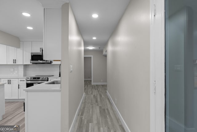 hallway with light wood-type flooring and sink