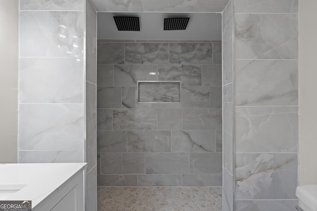 bathroom with vanity, toilet, and tiled shower