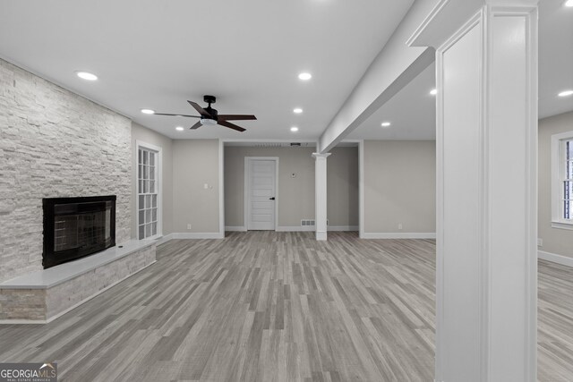 unfurnished living room featuring ceiling fan, a fireplace, and light hardwood / wood-style flooring