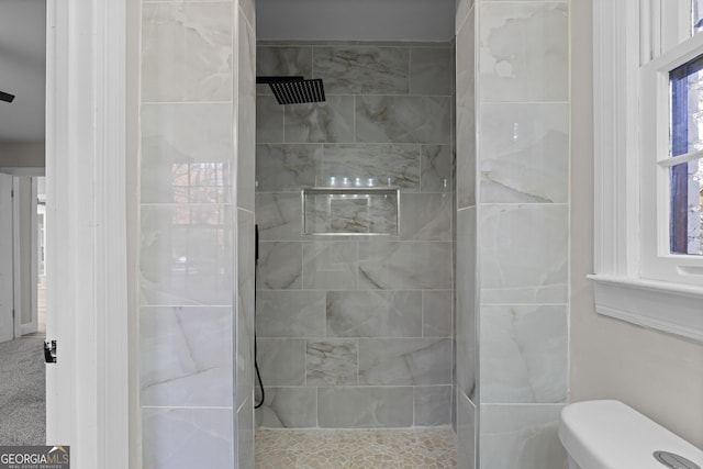 bathroom featuring a tile shower and toilet