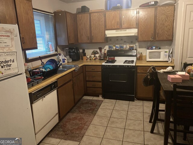 kitchen with light tile patterned flooring, white appliances, and sink