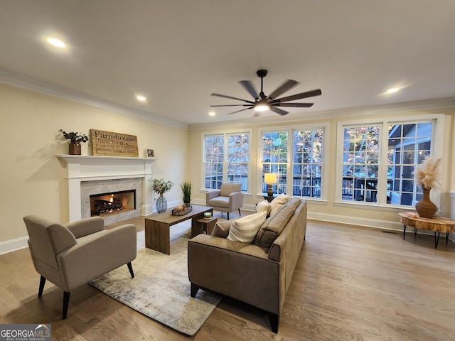 living room with hardwood / wood-style floors, ceiling fan, a premium fireplace, and crown molding